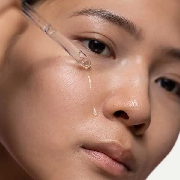 Woman applying skin care using a product dropper